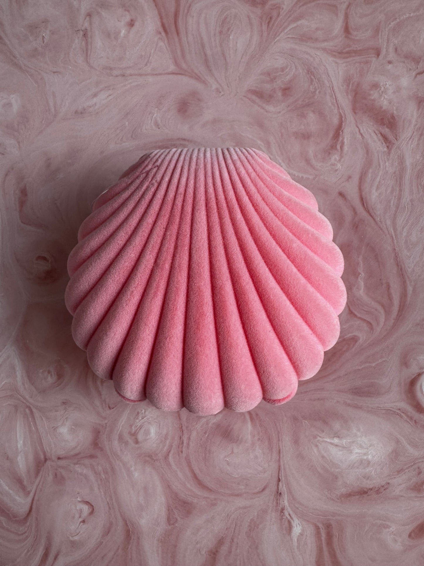 Pink shell-shaped object on a pink marbled background
