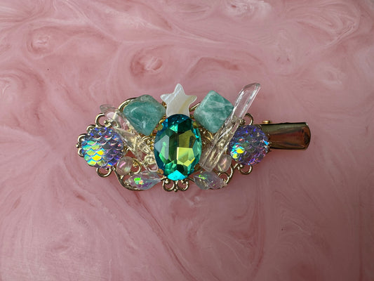 Decorative hair clip with gemstones on a pink marbled background