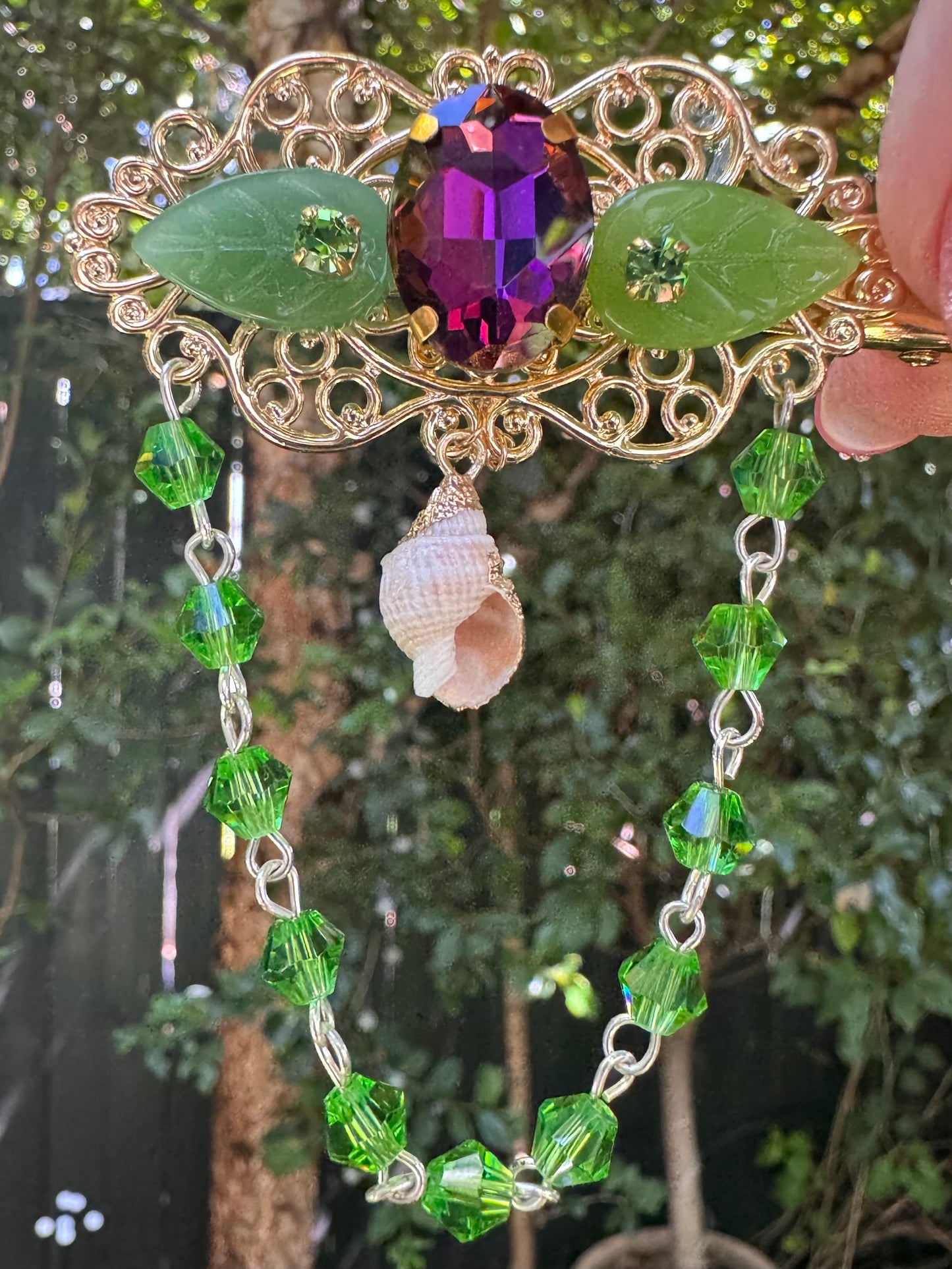 Decorative hair accessory with gemstones and green beads against a natural background