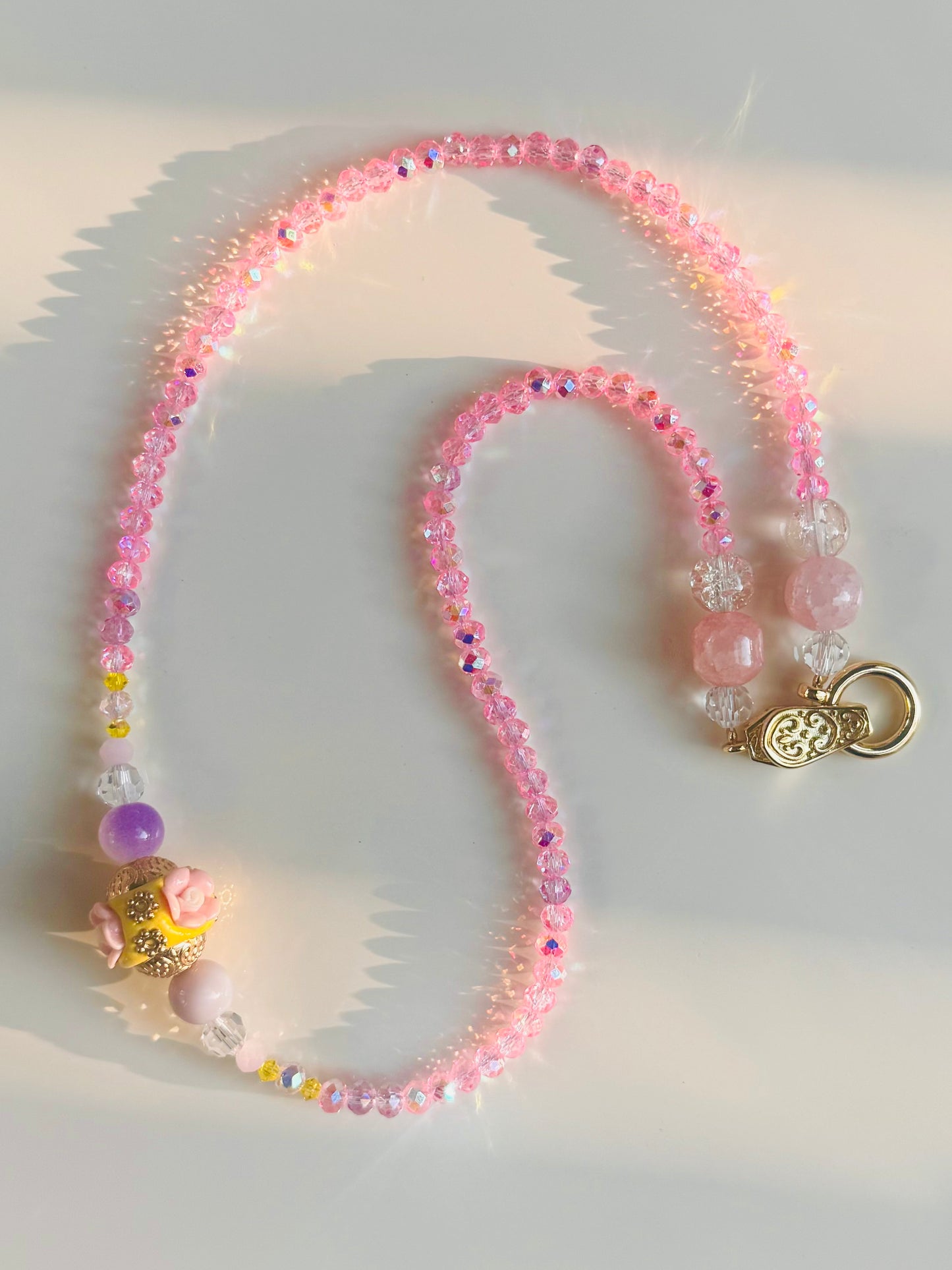 Pink beaded necklace with a gold clasp on a light background