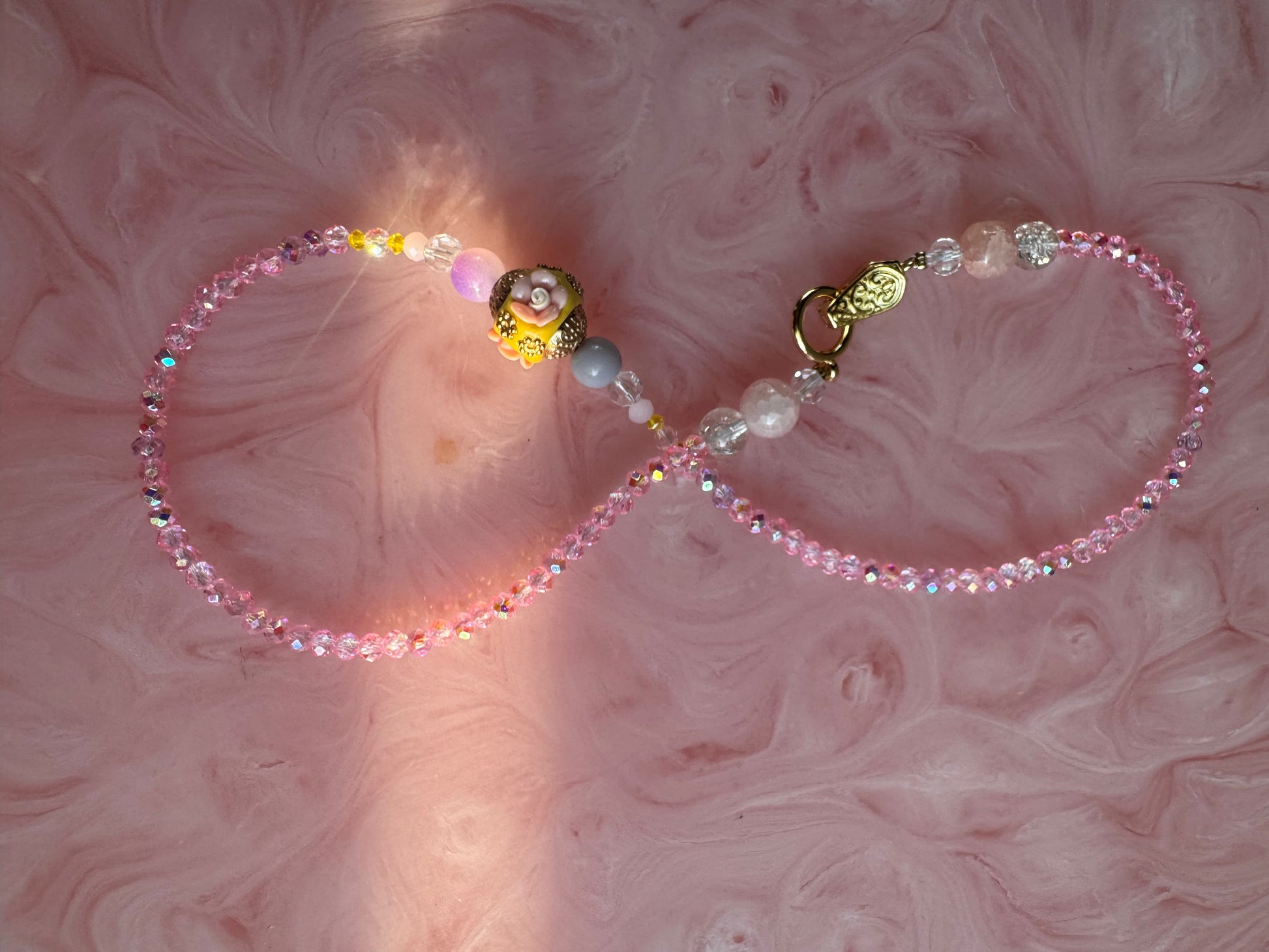 Beaded lanyard with decorative elements on a pink textured background