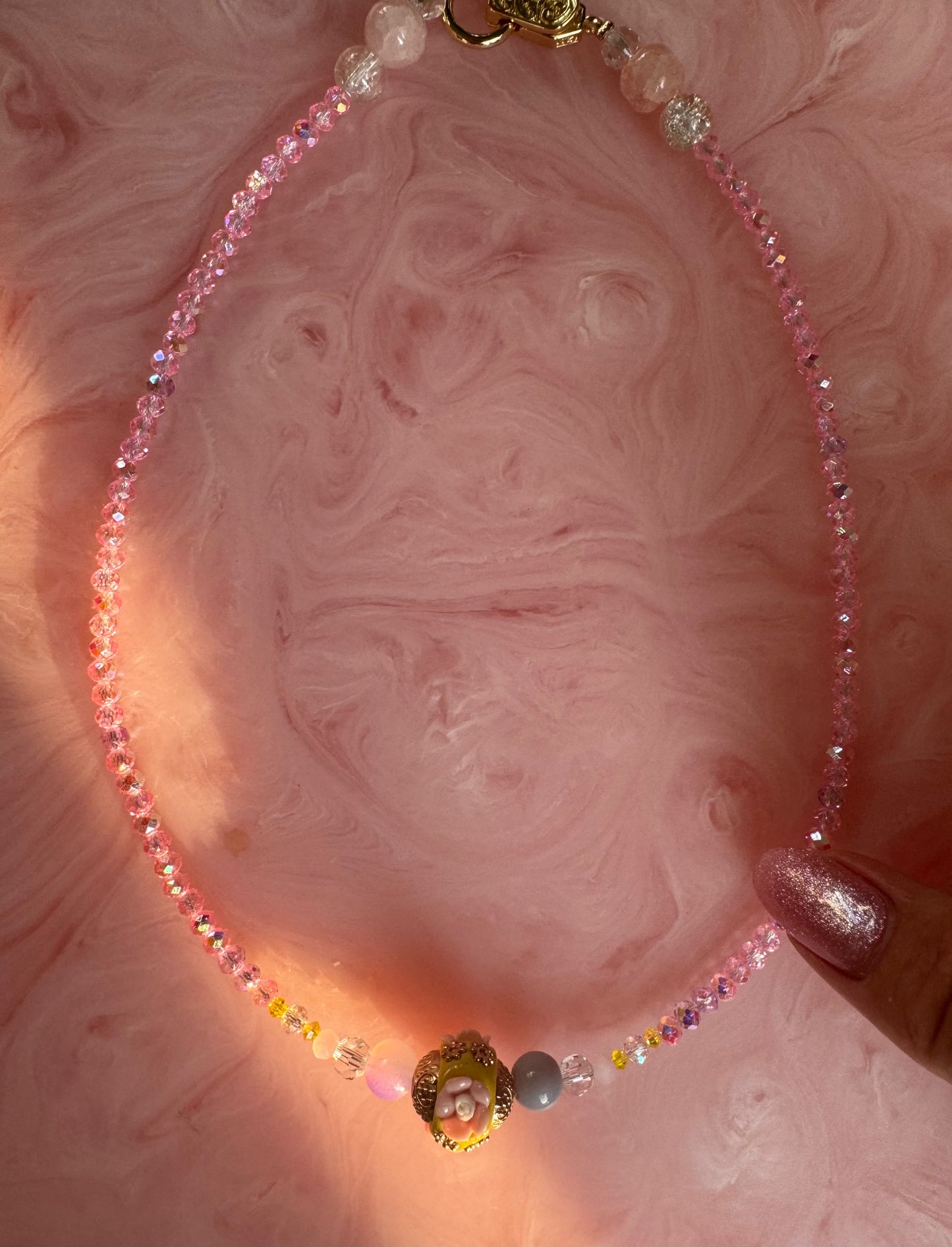 Necklace with colorful beads on a pink textured background