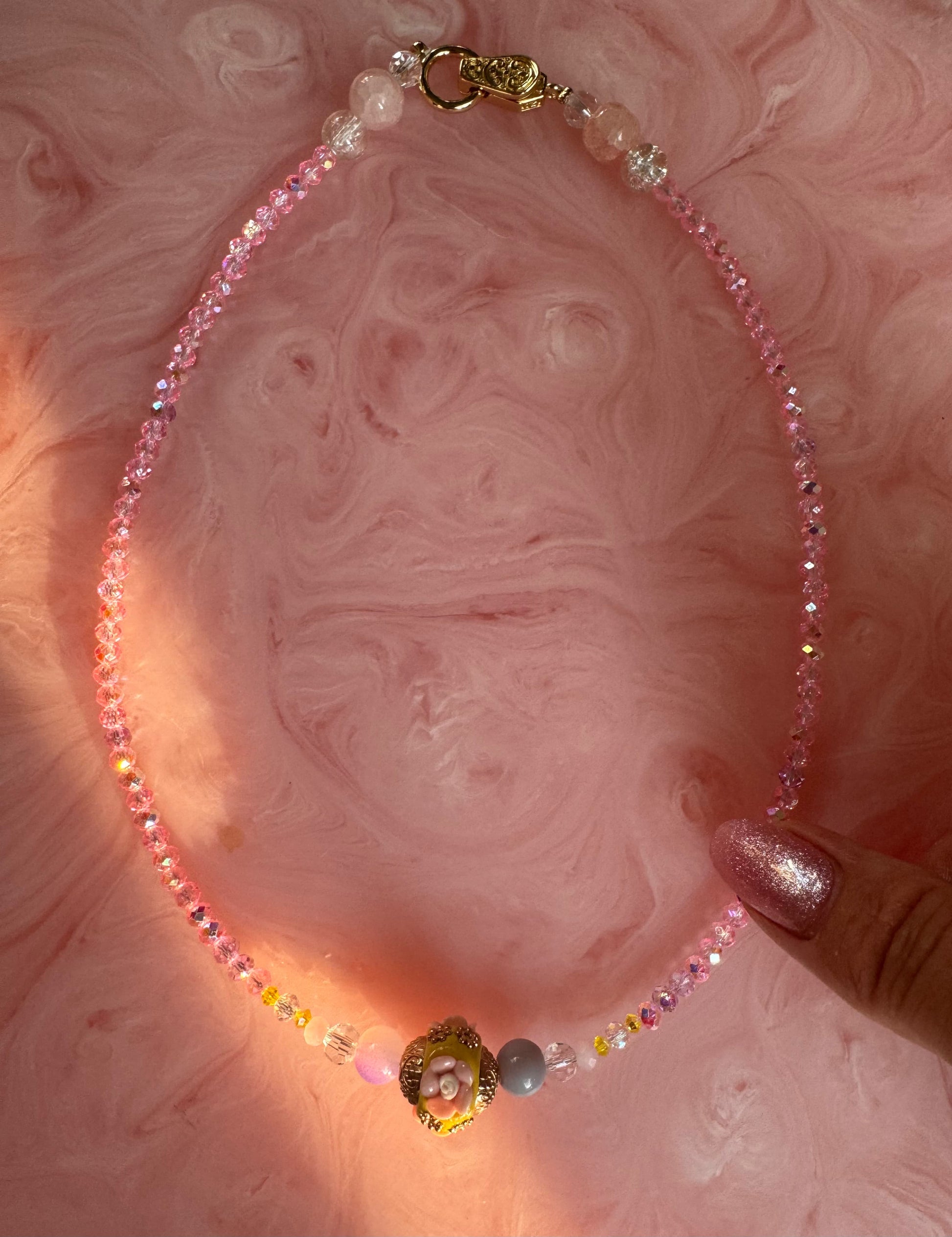 Necklace with colorful beads on a pink marbled background