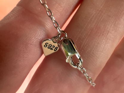 Silver clasp on a chain held between fingers with '925' stamp
