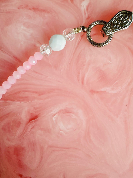 Necklace with pink beads and a decorative clasp on a pink textured background