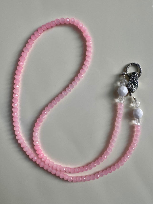 Pink beaded necklace with a silver clasp on a gray background