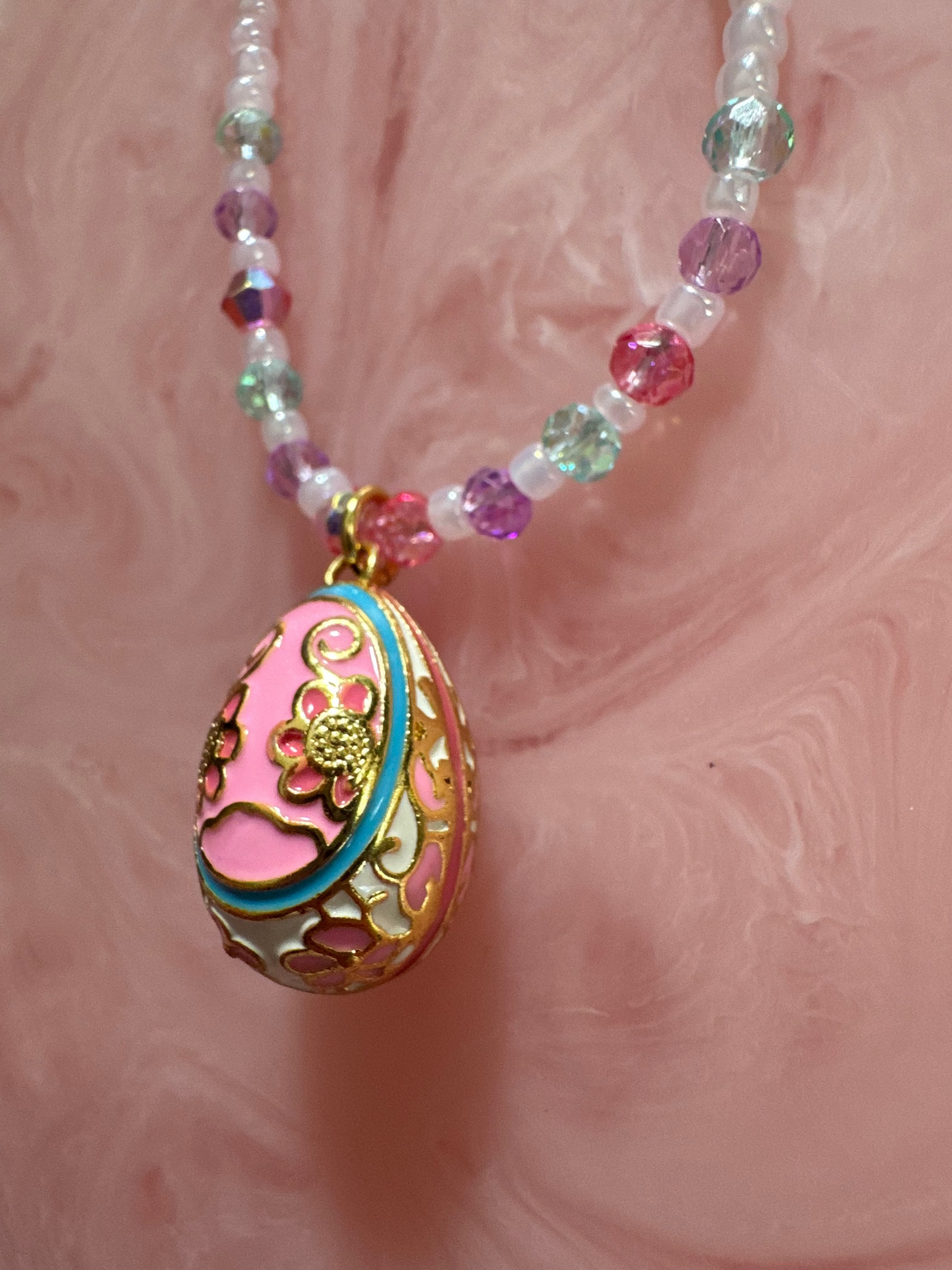 Decorative pink egg-shaped object with intricate designs on a pink textured background