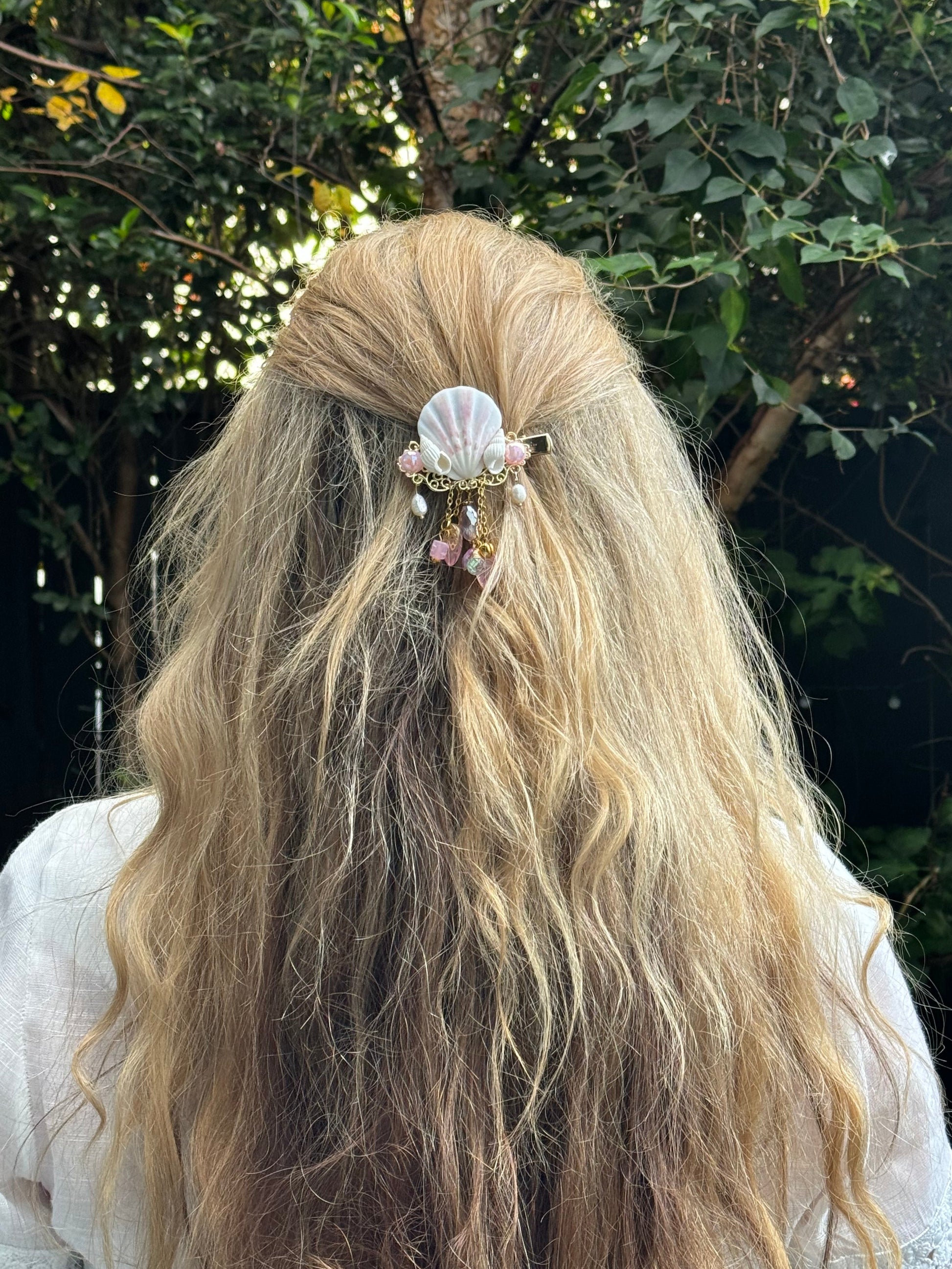 Person with long blonde hair wearing a decorative hair clip against a natural background