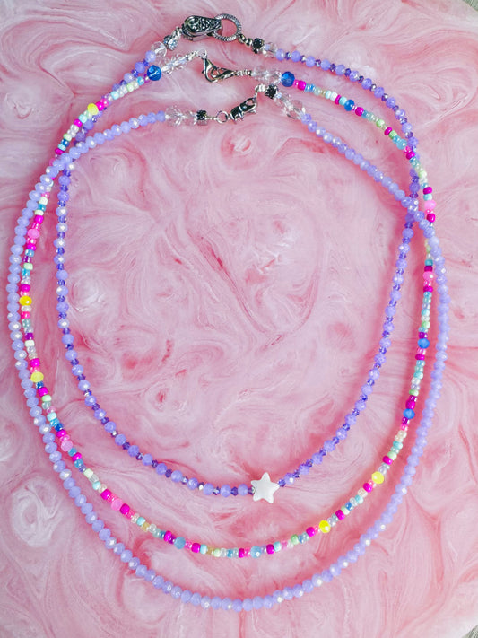 Multicolored beaded necklace on a pink marble background