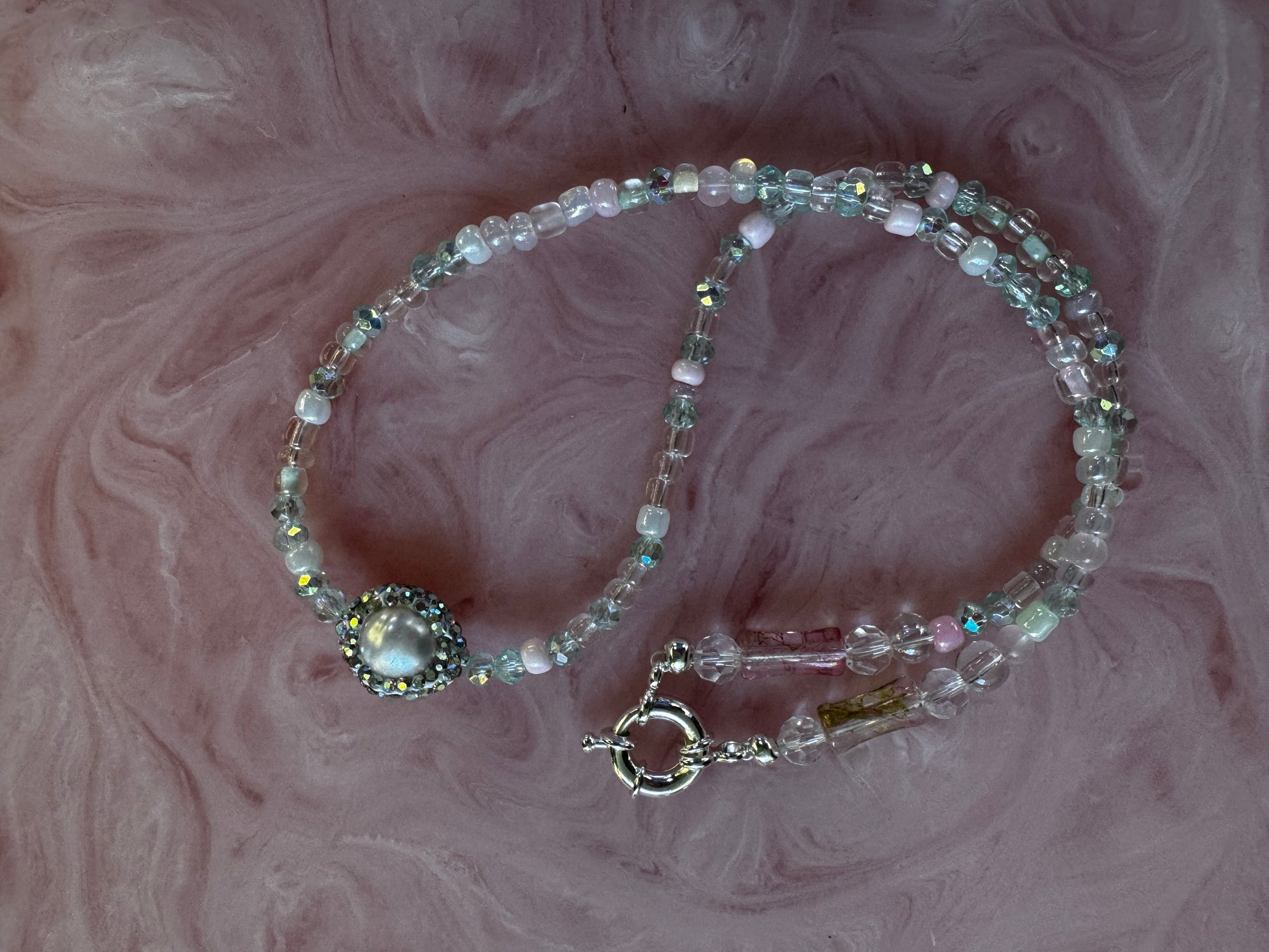 Beaded bracelet with a clasp on a marbled pink background