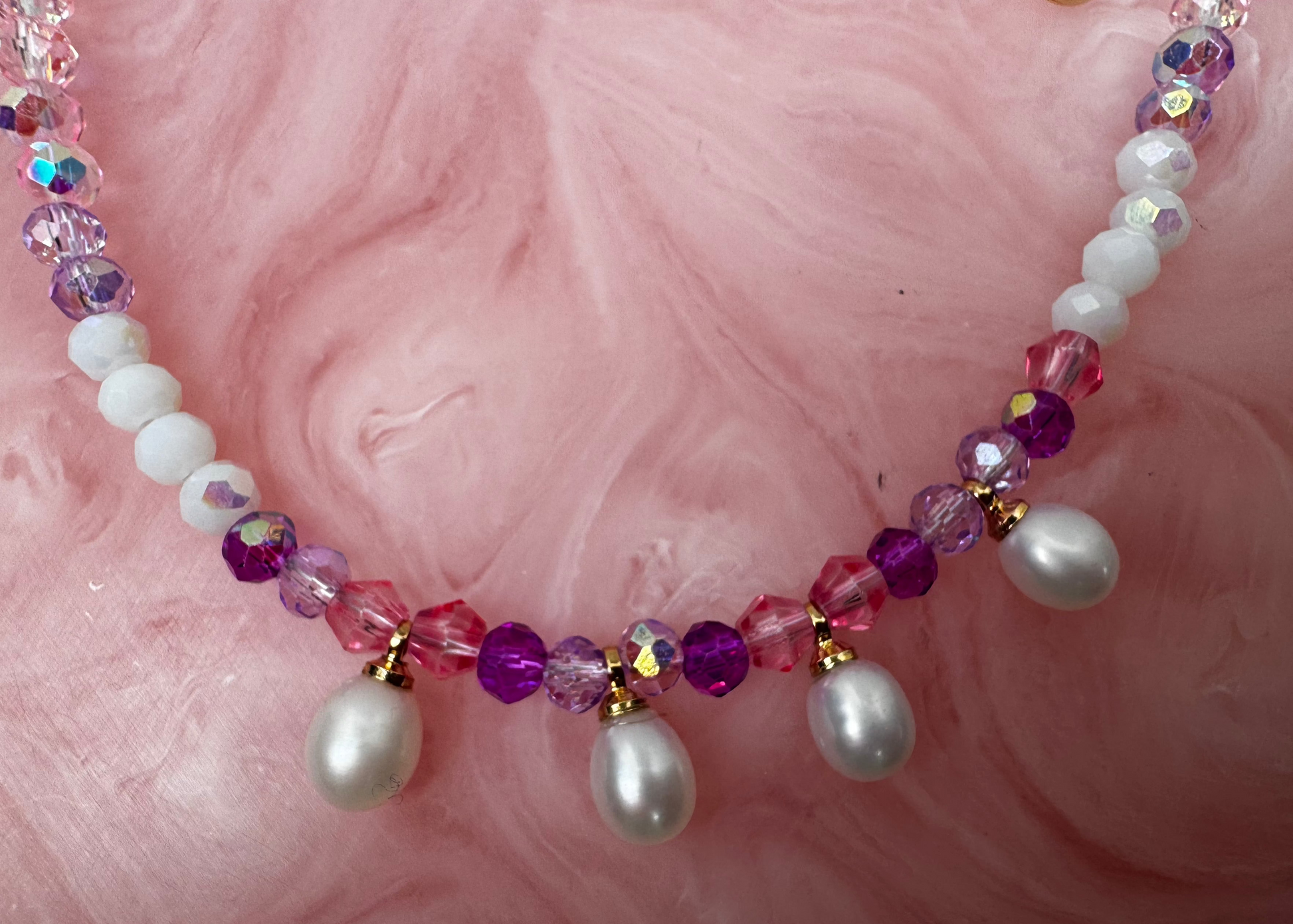 Beaded bracelet with pearls and multicolored beads on a pink textured background